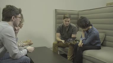 Men and women holding digital tablet and having discussion in office