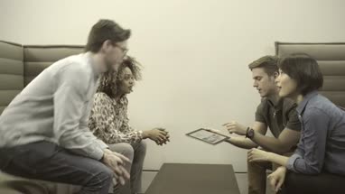 Men and women holding digital tablet and having discussion in office