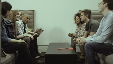Men and women sitting together and having discussion with digital tablet in office