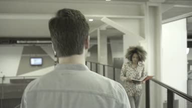 Man and woman talking while walking in office lobby