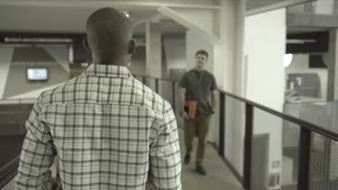 Men talking each other while walking in office lobby