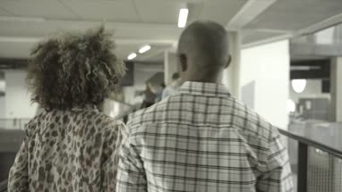 Men and woman greeting while walking in office lobby
