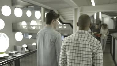 Men and woman greeting while walking in office lobby