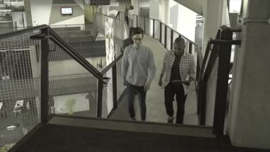 Men holding digital tablet and having discussion while walking in office lobby