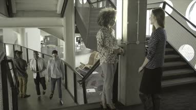 Men holding digital tablet and having discussion while walking in office lobby