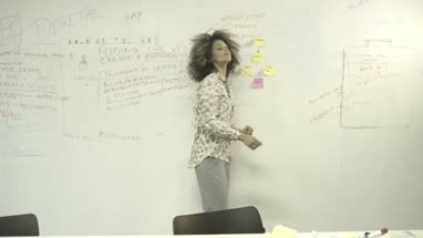 Young woman sticking adhesive note on notice board in office