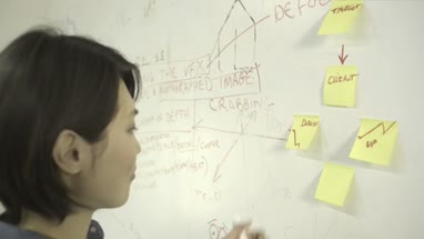 Woman sticking adhesive note and writing on notice board in office