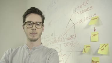 Young man sticking adhesive note on notice board in office