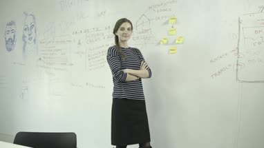 Young woman sticking adhesive note on notice board in office