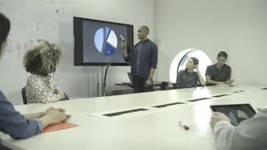 Man explaining pie chart during meeting in conference room
