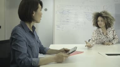 Men and women using digital tablet and having discussion in conference room