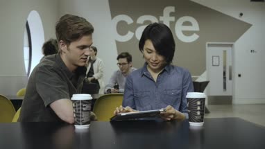 Man and woman using digital tablet and having discussion in office café