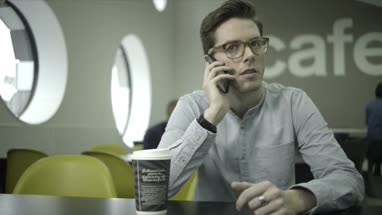 Young man sitting and talking on mobile in office café