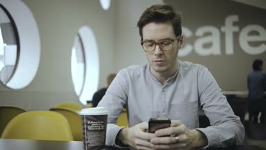 Young man text messaging on mobile phone in office café