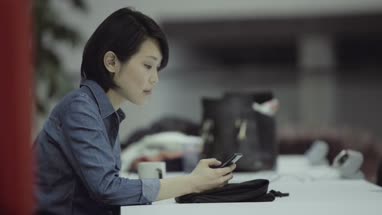 Woman sitting and using mobile phone in office