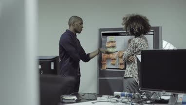 Man and woman standing nearby notice board and having discussion in office