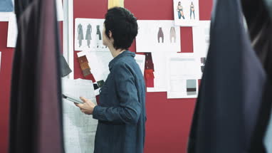 Fashion designer looking at designs in studio