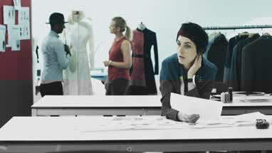 Fashion designers looking at digital tablet and clothes in studio