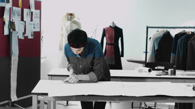 Fashion designers looking at digital tablet and clothes in studio