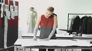 Fashion designer drawing in studio and making phone call 