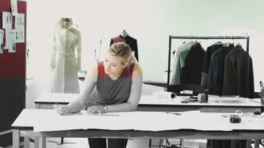 Fashion designers looking at digital tablet and clothes in studio