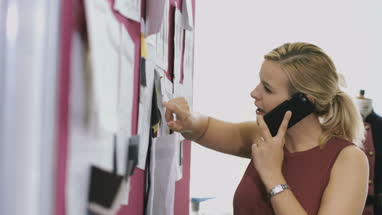 Fashion designer drawing in studio and making phone call 