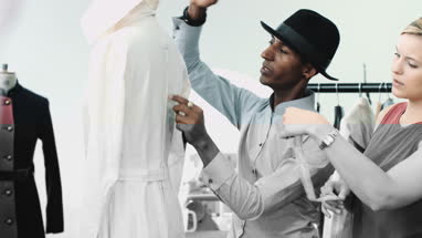 Fashion designer at work in studio training apprentice