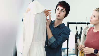 Fashion designer at work in studio training apprentice