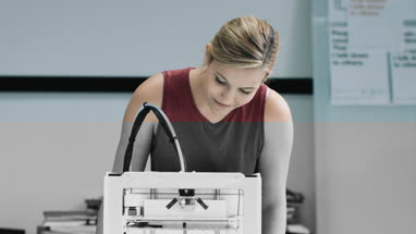 Female designer looking at 3D printer in studio