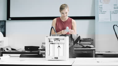 Female designer looking at 3D printed object in design studio
