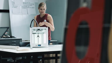 Female designer looking at 3D printed object in studio