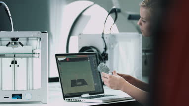 Female designer looking at 3D printed object in studio