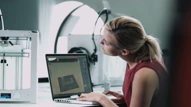Female designer looking at 3D printed object in studio