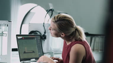 Female designer working with 3D printer and looking to camera