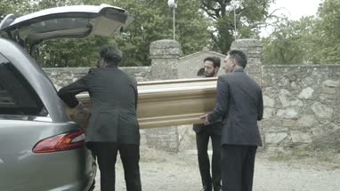Pallbearers in Hearse arriving with coffin at graveyard