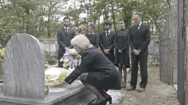 Senior woman laying flowers on grave