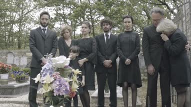 Mourners standing around grave