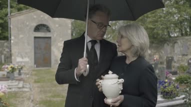 Mourners standing at funeral with cremation urn