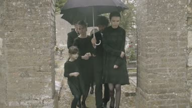 Mourners leaving graveyard in the rain