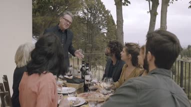 Senior giving speech to family at meal