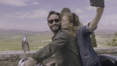 Couple on scooter taking selfie