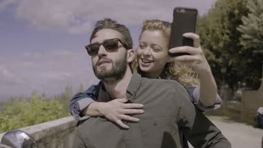 Couple on scooter taking selfie