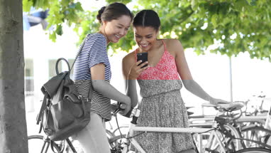 Young female friends socialising outdoors with bicycles