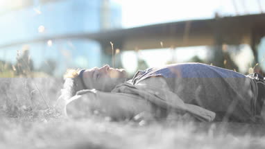 Trendy male sunbathing in long grass