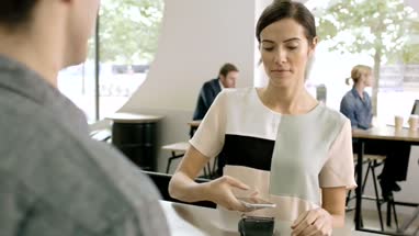 Business woman paying contactless in cafe and walking over to colleagues