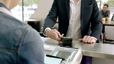 Business man paying contactless in cafe and walking over to colleagues