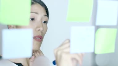 Native American Woman writing notes on window in creative office