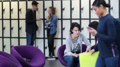 Students sharing digital tablet in break out space