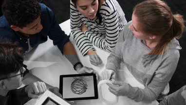 Students with digital tablet looking at prototype