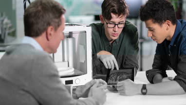 Students discussing 3D printer with teacher